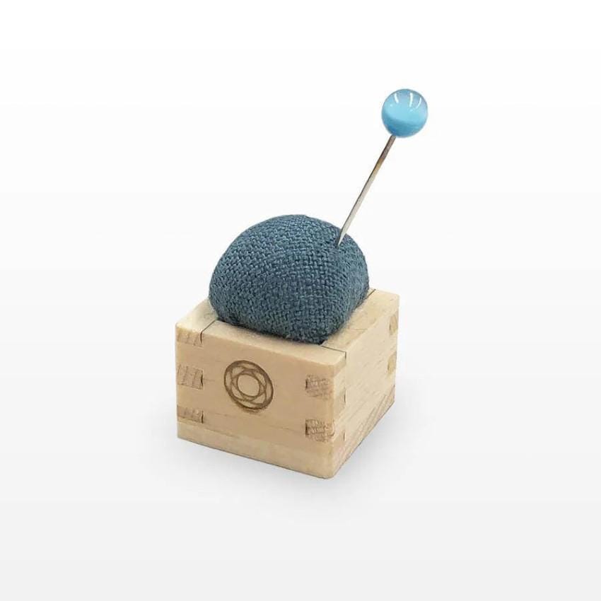 a blue ball of yarn sitting on top of a wooden block