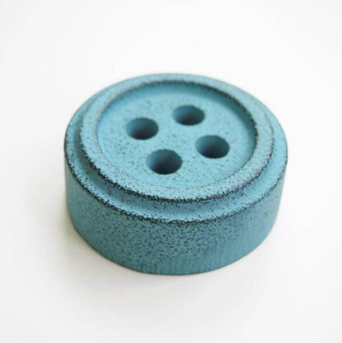 a blue button sitting on top of a white table