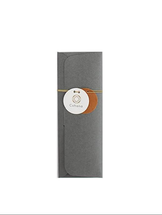 A gray envelope with a white circular label and a brown leather tag attached to it.