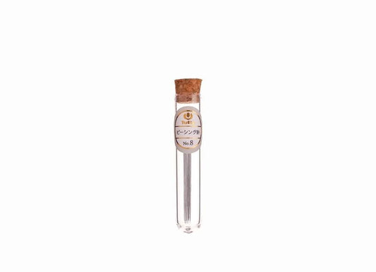 A clear glass tube with a cork stopper containing a metal object, possibly a pencil or pen, against a white background.