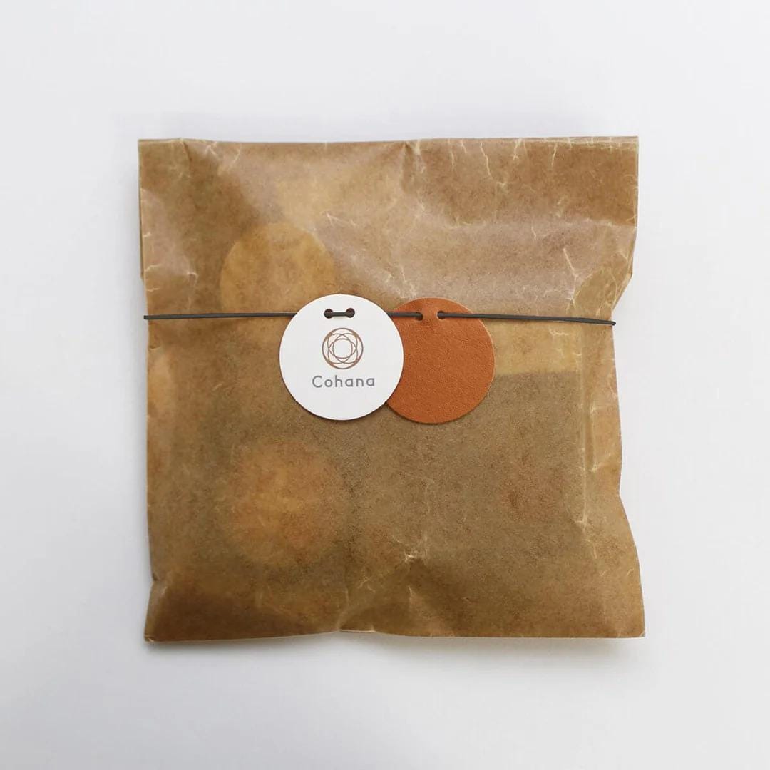 A brown paper bag with a round label and a brown leather tag attached to it.