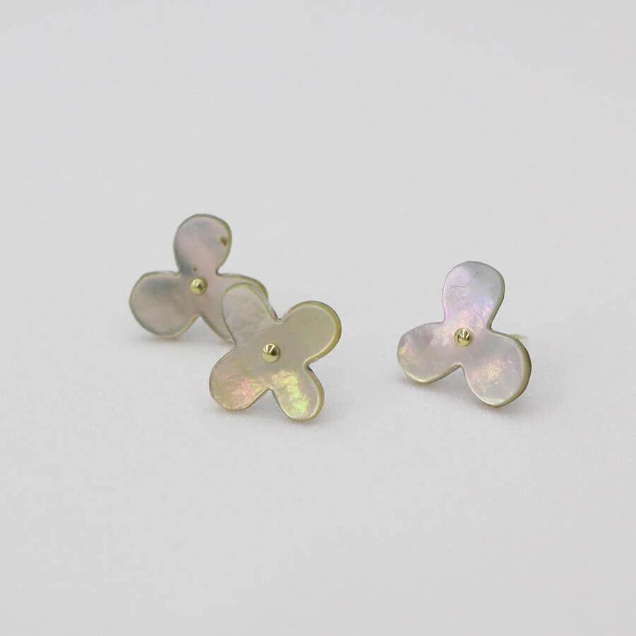 Three small, flower-shaped earrings with a light purple hue and gold accents are displayed against a white background.
