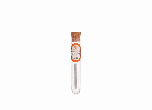 A clear glass tube with a cork stopper, containing a small object, is shown against a white background.