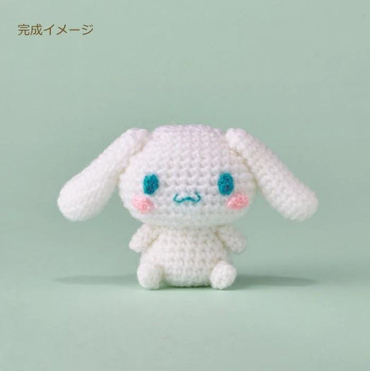 A crocheted white bunny with blue eyes and a pink nose sits on a light green background.