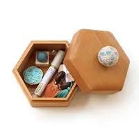 A wooden box with a lid, containing various items such as a blue and white ball, a white tube, and a small blue and white plate.