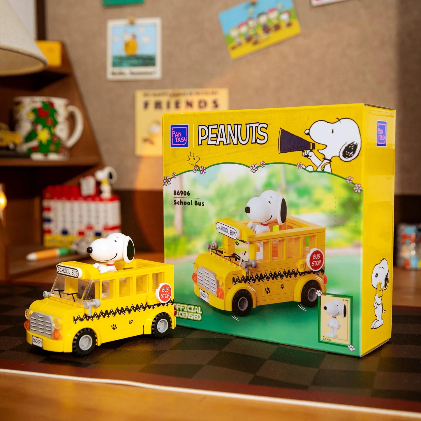 A yellow toy school bus with a cartoon character on the front, sitting on a table next to its packaging box.