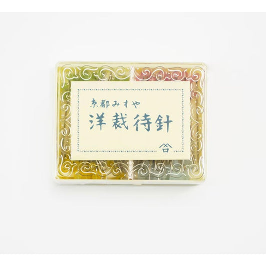 a square-shaped container with a decorative border, containing a variety of colorful objects. The container has a label with Japanese text on it, which appears to be a product description or information related to the contents of the container.