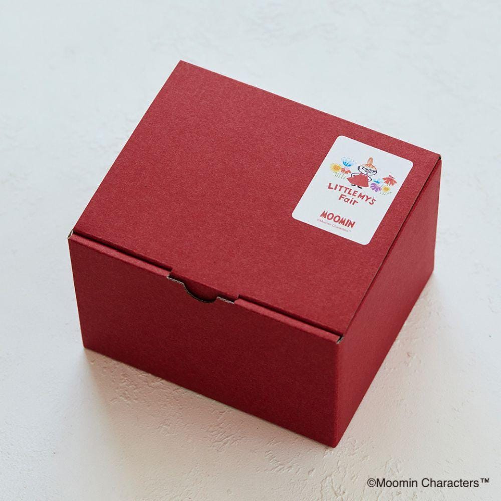 A red cardboard box with a label on it, sitting on a white surface.