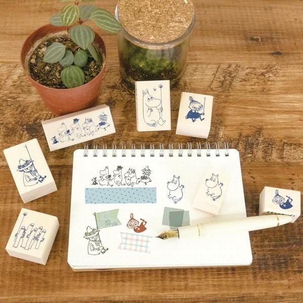 a notebook with various cartoon animal illustrations, a pen, and several wooden blocks with animal designs, all placed on a wooden surface.