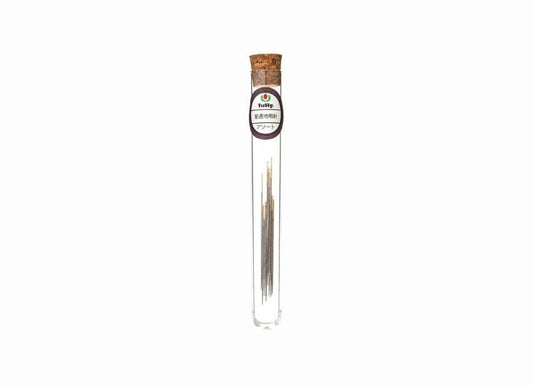 A clear glass tube with a cork stopper containing several small sticks or sticks of incense.