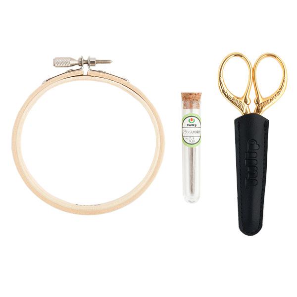 a pair of gold scissors, a gold hoop, and a tube of thread, all arranged in a row.
