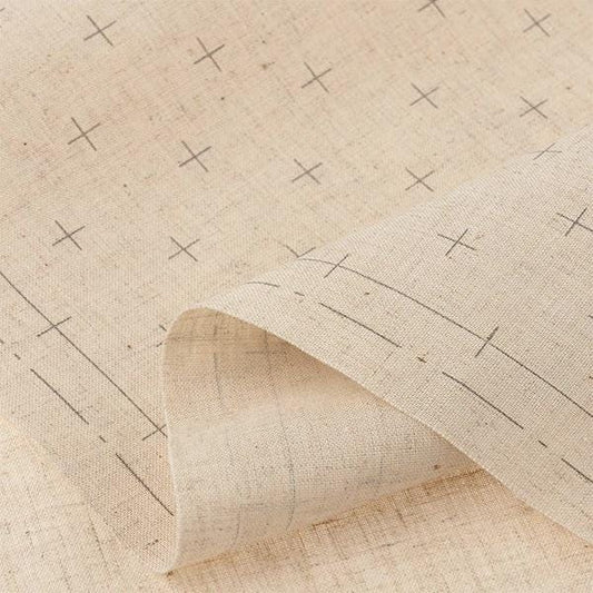 a close-up view of a fabric with a repeating pattern of black crosses on a beige background.