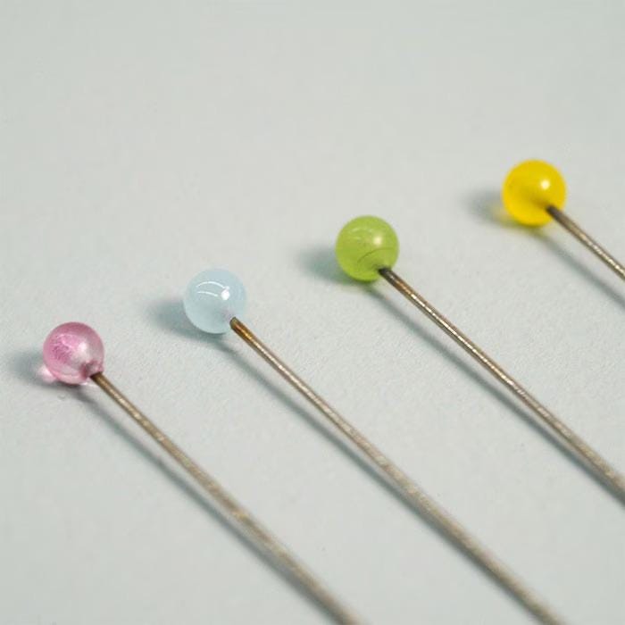 Four colorful beads on a grey background, arranged in a row.