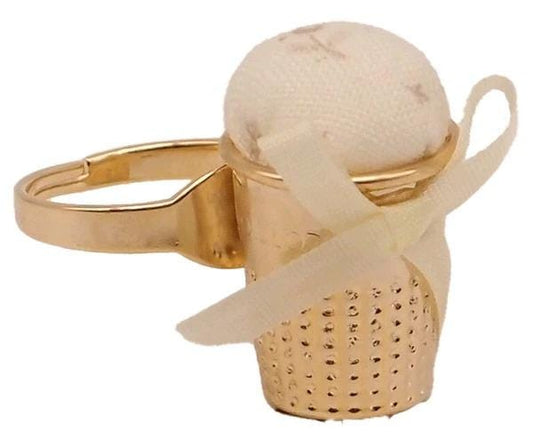 A gold-colored ring with a small white ball or object placed inside it, tied with a white ribbon.