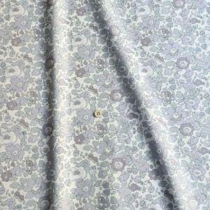 a close-up view of a fabric with a floral pattern, featuring a single button in the center.