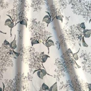 a close-up view of a fabric with a repeating pattern of gray and white flowers and leaves.