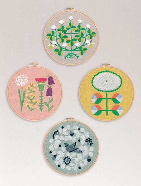 four circular embroidery pieces, each with a unique floral design. The designs include a variety of flowers and leaves, creating a diverse and visually appealing collection.