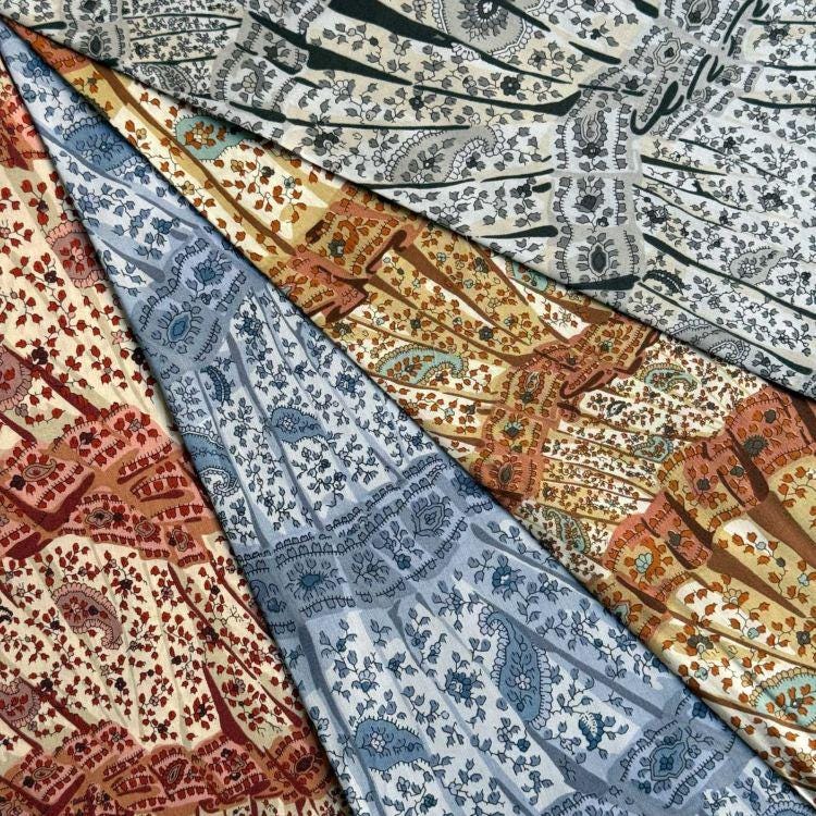 The image is a close-up of a fabric with a variety of colorful and intricate patterns, including paisley designs and floral motifs.