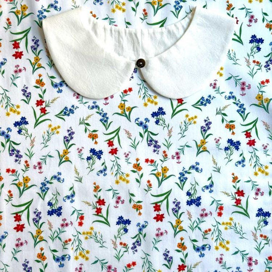 a white collar with a button, set against a background with a colorful floral print.