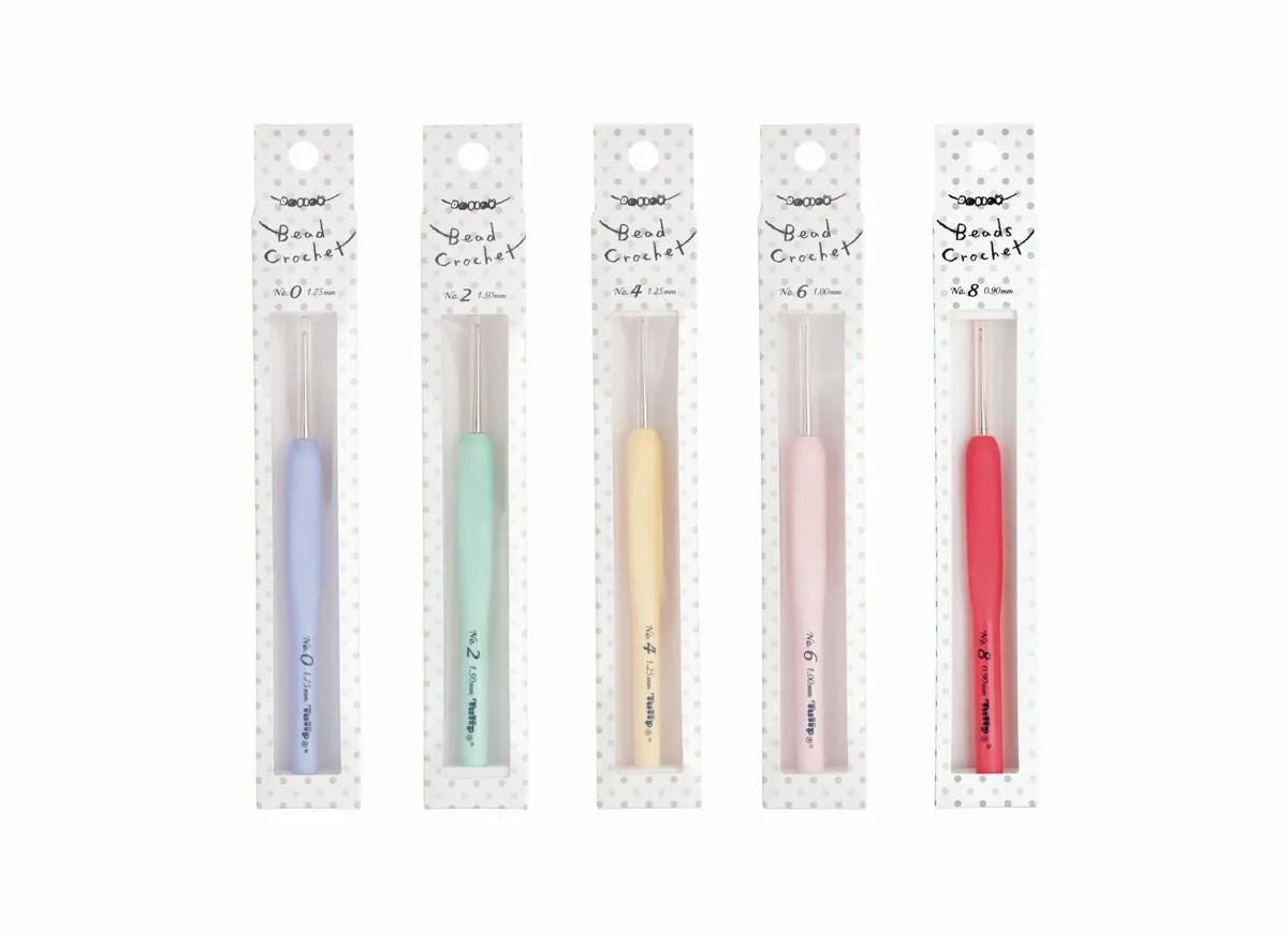 five crochet hooks in different colors, each packaged in its own clear plastic case.