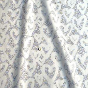 a close-up view of a fabric with a repeating pattern of white hearts. The fabric appears to be made of a soft, plush material, possibly cotton or a similar type of material. The pattern of the fabric is intricate and detailed, with the hearts appearing in various sizes and orientations. The fabric is folded and crumpled, giving it a soft and delicate appearance.