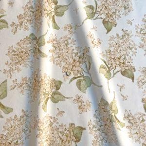 a close-up view of a fabric with a floral pattern, featuring white flowers and green leaves.