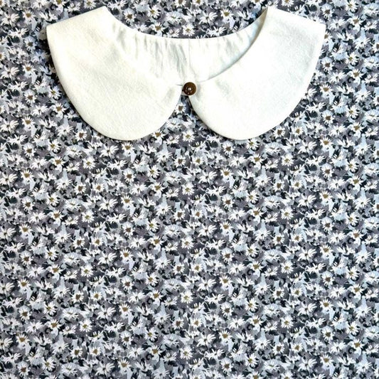 a white collar with a button, set against a background of a floral print fabric.