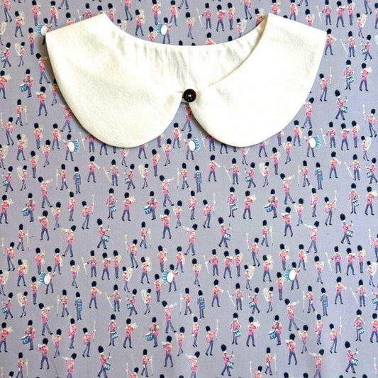 a white collar with a black button, placed on a background with a repeating pattern of people playing musical instruments.