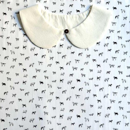 a white collar with a button, placed on a background with a repeating pattern of black and white dog illustrations.