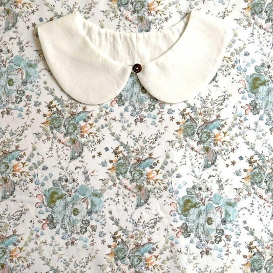 a white collar with a button, set against a floral print background.