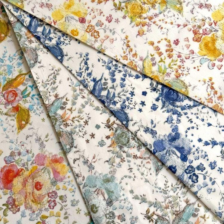 The image is a close-up of a collection of fabric swatches with various floral patterns, including yellow, blue, and orange flowers.