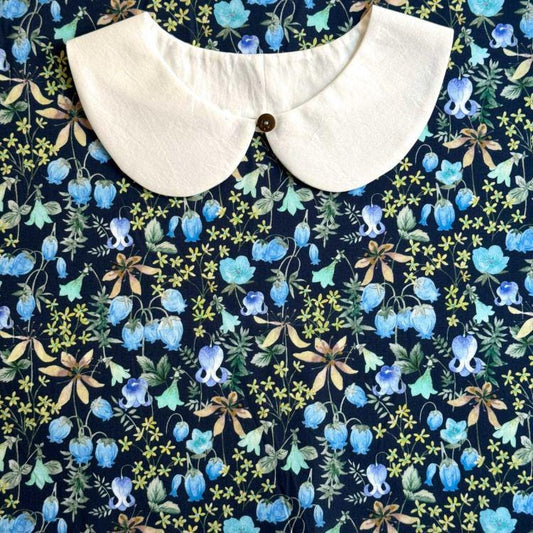 a white collar against a background with a floral pattern in shades of blue, green, and yellow.