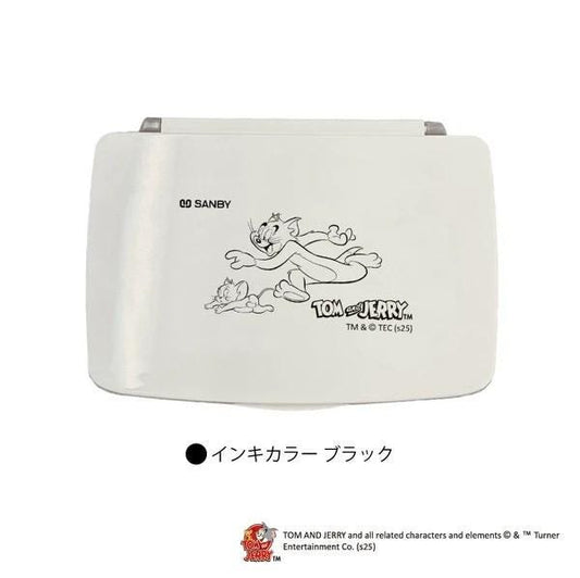 A white rectangular object with a cartoon image of two cats, one larger and one smaller, on it. The cats appear to be in motion, running or jumping. The object has a logo or text that reads "Tom and Jerry" and "TM & © (25)".