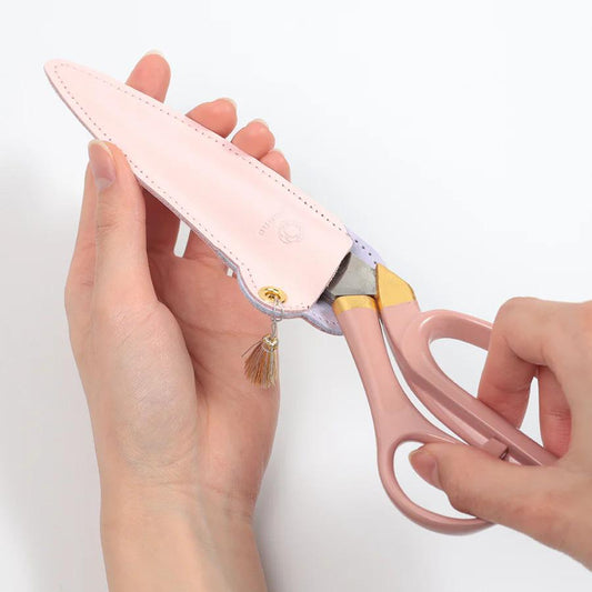 A pair of pink scissors being held by a person's hand.