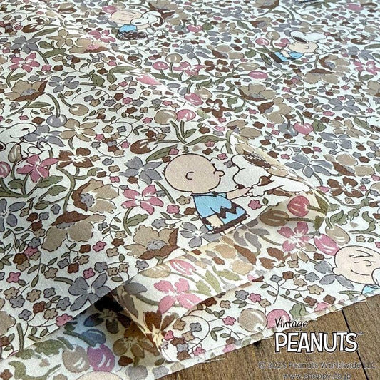 a close-up view of a fabric with a floral pattern and cartoon characters, including the Peanuts characters.