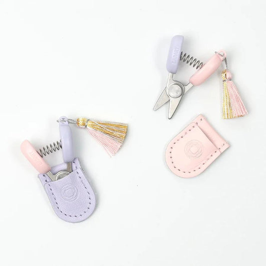 a pair of scissors with tassels and a keychain attached to them, placed on a white background.
