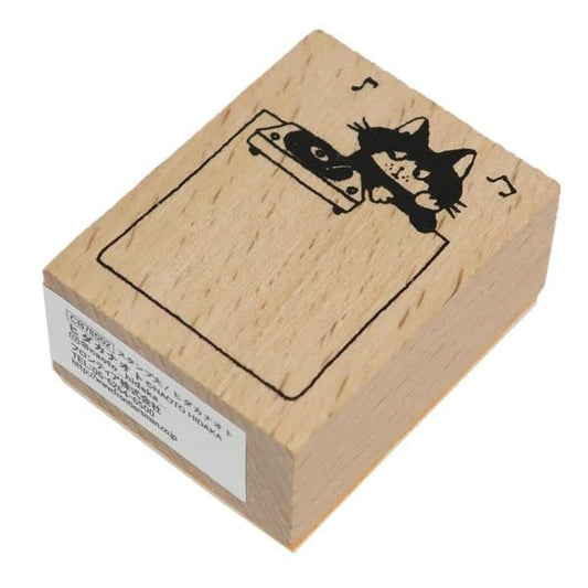 A wooden stamp with a black cat illustration on it.