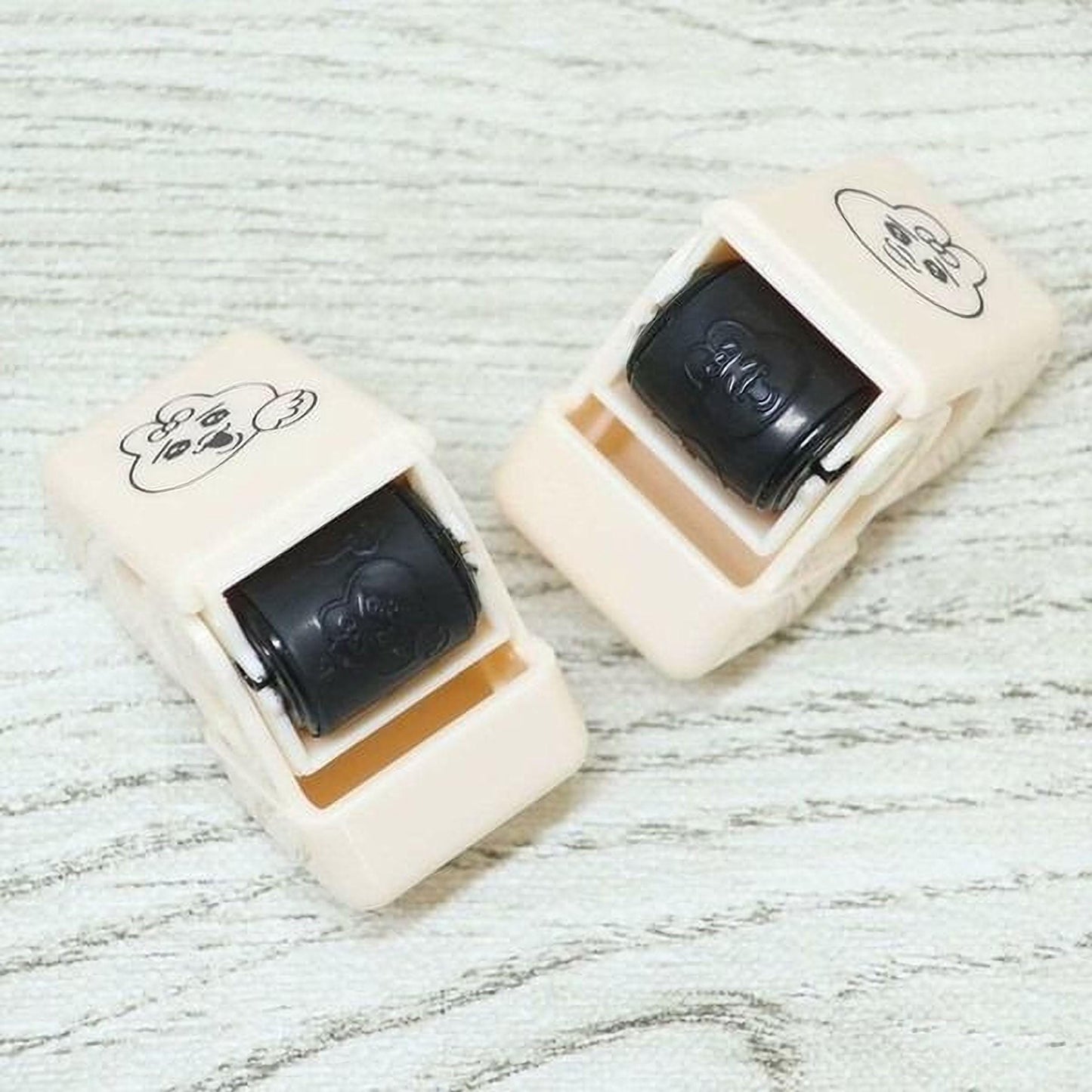 Two white and black push-button devices with black buttons are placed on a wooden surface.