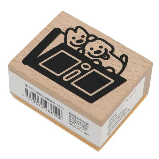 A wooden stamp with a black and white illustration of two dogs sitting on a table.