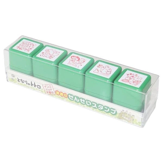 A clear plastic container holding five green plastic stamp holders with red and white designs on them.