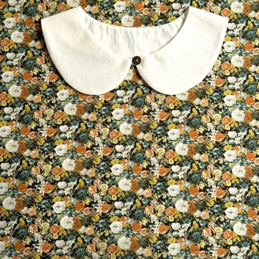 a white collar with a button, set against a background of a colorful floral print.