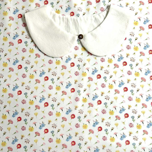 a white collar with a button, set against a background with a floral print.