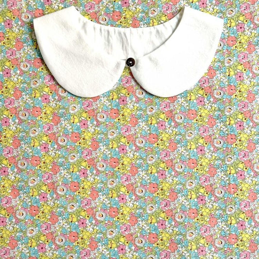 A white collar is displayed against a colorful floral background.