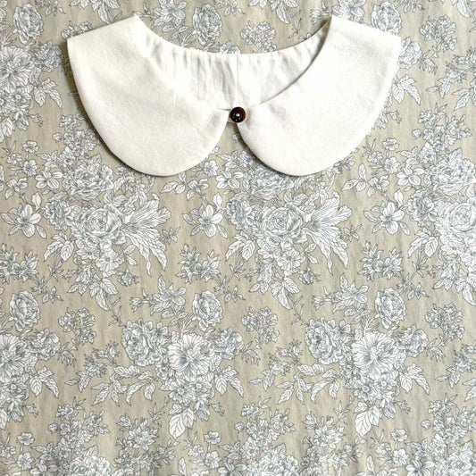 a white collar with a button, set against a floral print background.