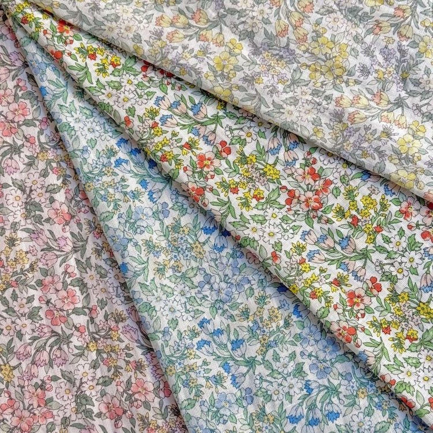 a collection of fabric swatches with various floral patterns, including pink, blue, green, and yellow flowers.