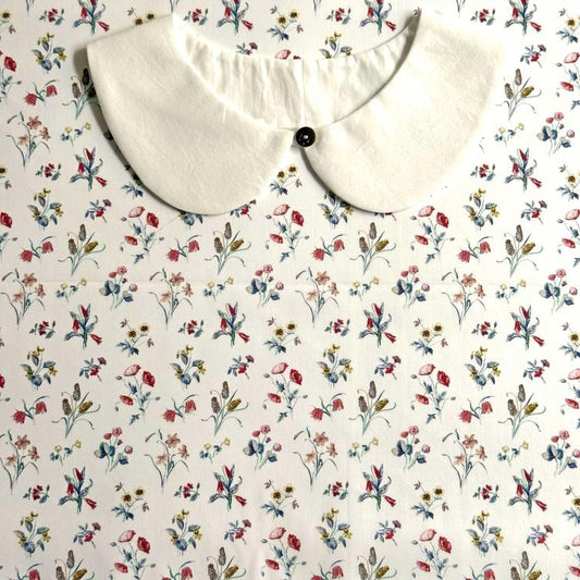 a white collar with a button, set against a background with a floral print.