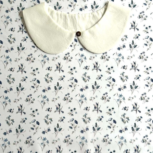 a white collar with a button, set against a background with a floral print.