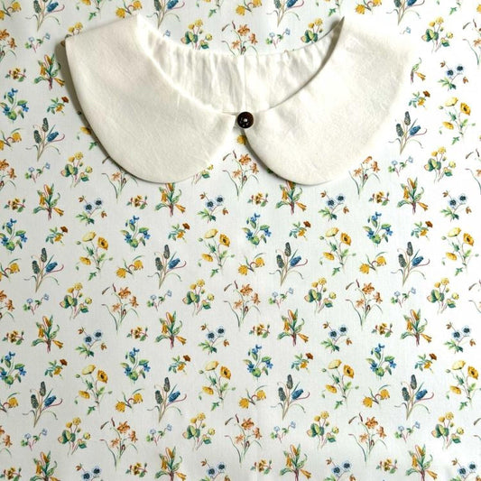 a white collar with a button, set against a background with a floral print.