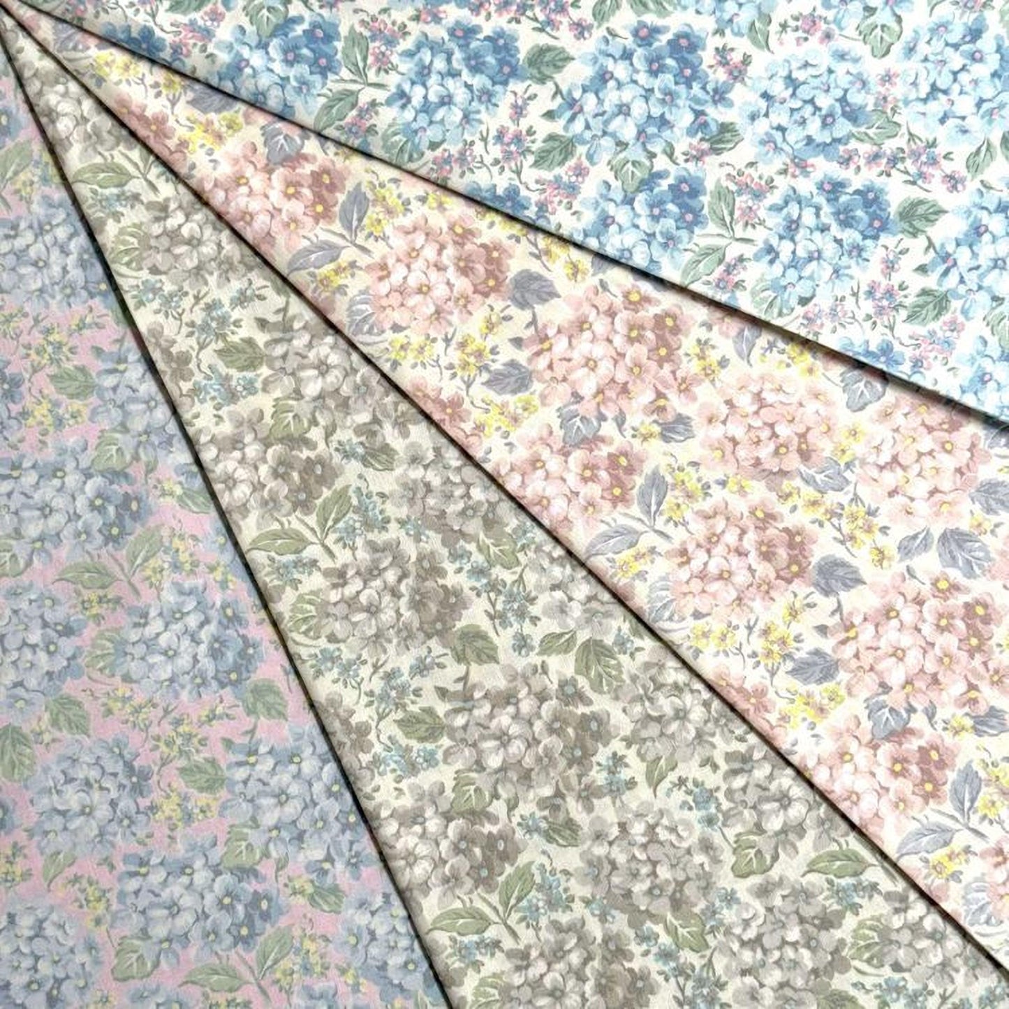 a collection of fabric swatches with various floral patterns, including blue, pink, and white flowers.