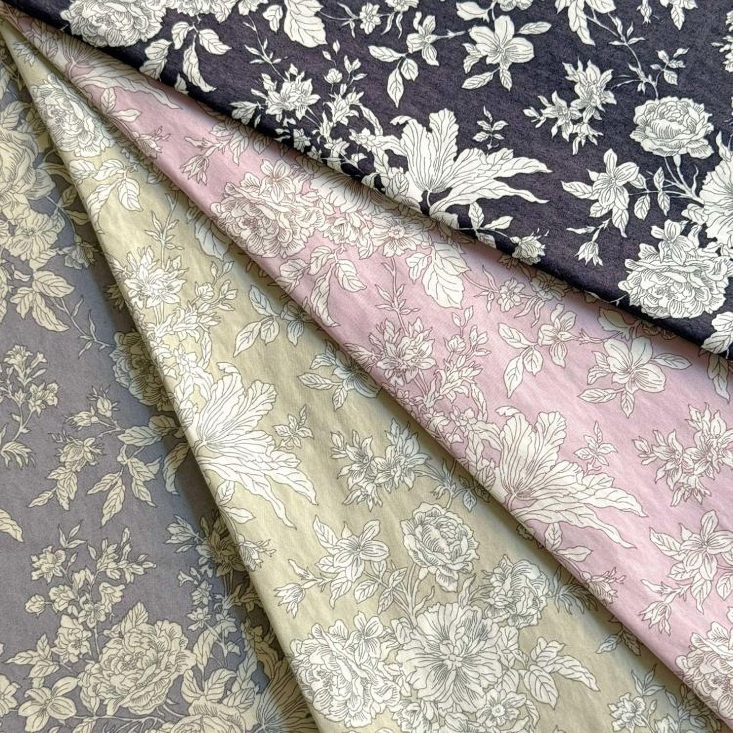 four fabric swatches with floral patterns in various shades of gray, pink, and blue.
